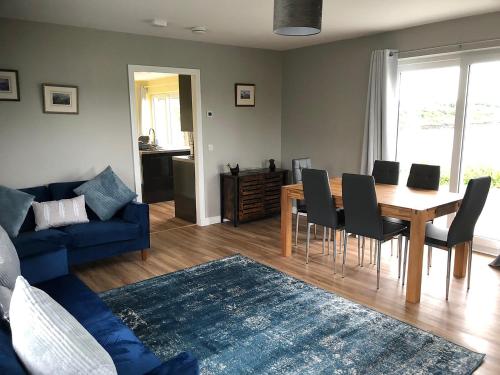 a living room with a dining table and a blue couch at Caroy Bay Cottage-Uk32669 in Harlosh