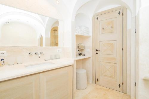 a bathroom with a sink and a mirror and a door at Luxury Pevero Apartment in Golf Club in Abbiadori