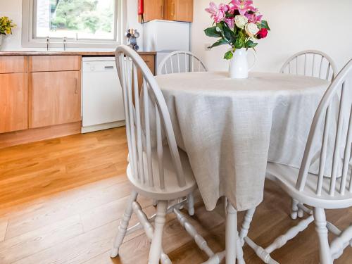 a kitchen table with a vase of flowers on it at Rowan Lodge in Resolis