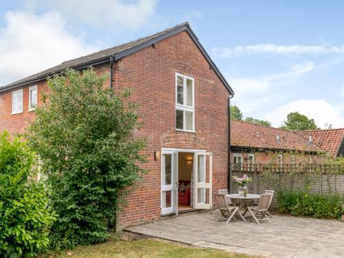 a brick house with a patio and a table at Coach House - Uk33307 in Mellis