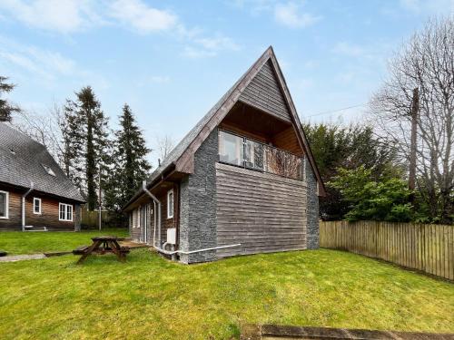 a small house with a gambrel roof on a yard at Ptarmigan Lodge in Balmaha
