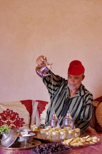 a man in a red hat drinking from a bottle at Dar Tamzdamte Skoura in Skoura