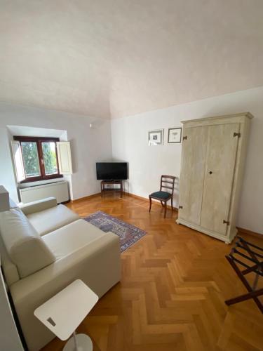 a living room with a white couch and a television at Villa I Barronci Resort & Spa in San Casciano in Val di Pesa