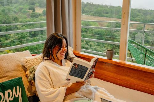 a woman sitting on a couch reading a book at Casa Ejecutiva Boquete in Boquete