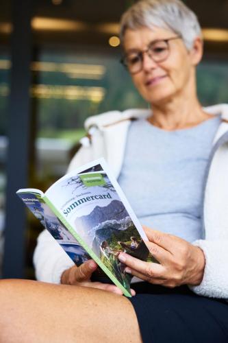 an older woman reading a book while sitting at Hotel UND - smart alpine stay in Schladming