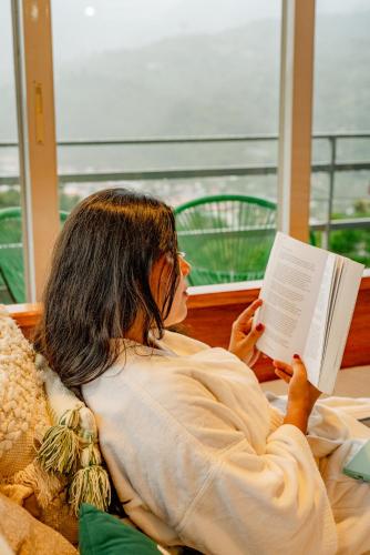 a woman laying in bed reading a book at Casa Ejecutiva Boquete in Boquete