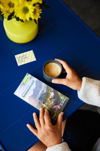 a person sitting at a blue table with a cup of coffee at Hotel UND - smart alpine stay in Schladming