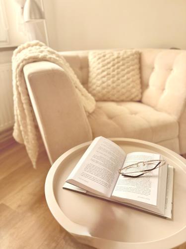 a coffee table with a book and glasses on it at Trio Apartments in Ostrava