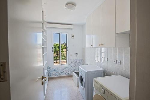 une cuisine blanche avec une machine à laver et une fenêtre dans l'établissement Villa Mavris - Lovely 4 Bedroom Villa With Private Pool In Central Ayia Napa, à Ayia Napa