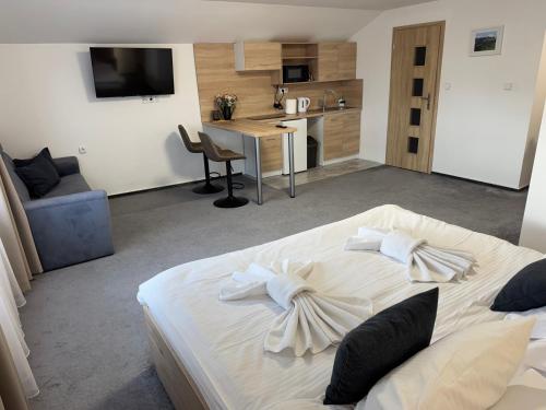 a bedroom with a large white bed and a kitchen at Penzión Čikovský in Stará Lesná