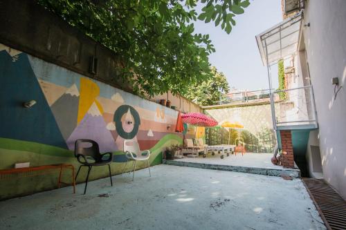 ベオグラードにあるHostel Bongoの椅子が2脚置かれた壁と壁画が描かれた壁