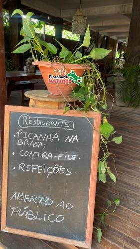 a chalkboard sign with a potted plant on top of it at Pousada Kalango in Barra Grande