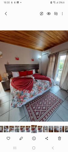 a bedroom with a bed with red sheets and a rug at Courtlyguesthouse in Witbank