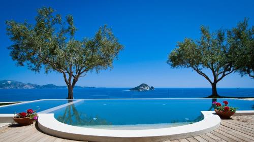 a swimming pool with trees and the ocean in the background at Kymaros Villas in Keri