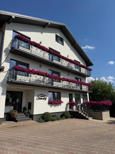 a white building with balconies and flowers on it at Penzión Čikovský in Stará Lesná
