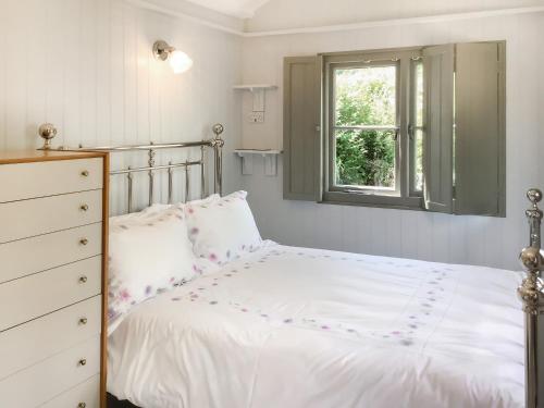 a bedroom with a white bed and a window at Fig Tree Shepherds Hut - Cottage in Bridport