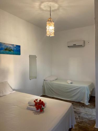 a room with two beds with flowers on a table at Pousada Kalango in Barra Grande