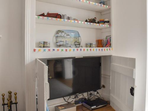 a flat screen tv in a living room with a shelf at Sunnyside in West Mersea