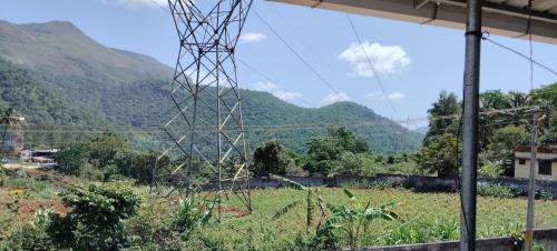 an electricity tower in a field with mountains in the background at MKV HomeStay Marayoor in Marayoor