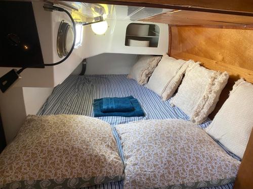 a small room with a bed and pillows on a boat at Séjour insolite à bord d'un voilier de 11m - Charmante Marina proche Barcelone in Sitges