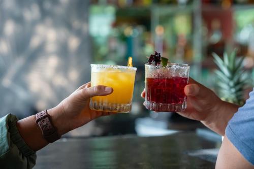 two people are holding up two drinks at Lake Arenal Hotel & Brewery in Tilarán