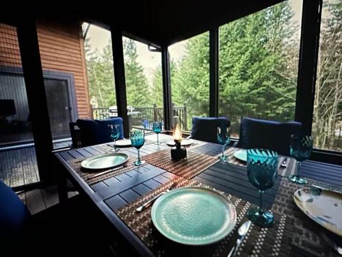 a wooden table with plates and wine glasses on it at Luxury with hot tub 300mbps Wifi Games & more ! in Saint Adolphe D'Howard