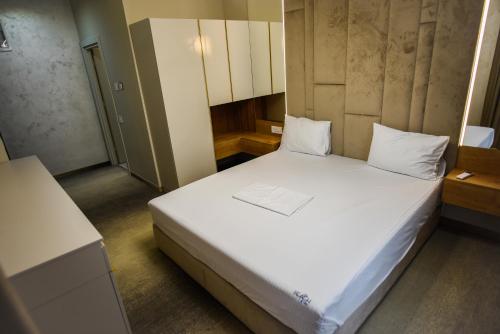 a small bedroom with a bed with white sheets at Beach Vibe Hotel Mamaia Nord in Mamaia Nord