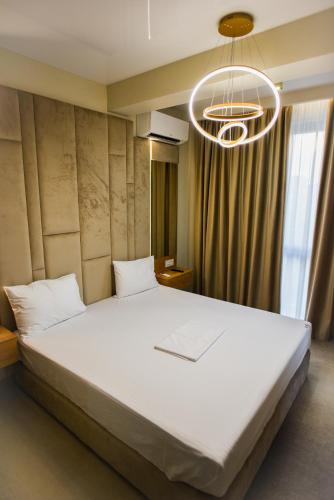 a bedroom with a large bed and a chandelier at Beach Vibe Hotel Mamaia Nord in Mamaia Nord