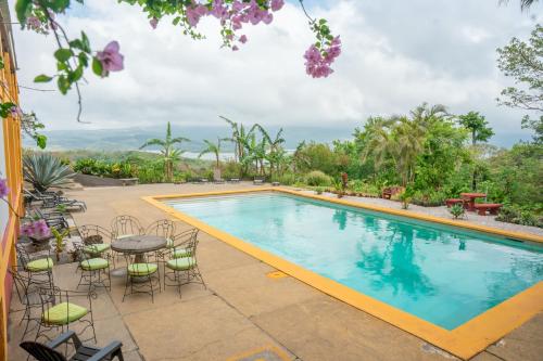 a swimming pool with chairs and a table next to it at Lake Arenal Hotel & Brewery in Tilarán