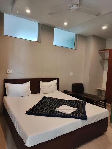 a bedroom with a bed with white sheets and two windows at Hotel Green Land in Mohali