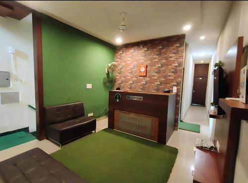 a living room with a couch and a green wall at Hotel Green Land in Mohali