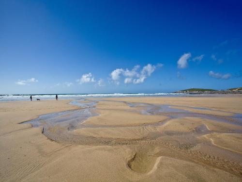 a beach with a group of people in the water at Fistral Escape in Crantock