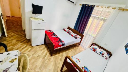 a small room with two beds and a television at Vila Brahimasi in Durrës