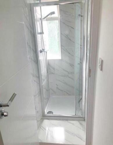 a shower with a glass door in a bathroom at Sunny Gardens 3-Bed Apartment in London in Hendon