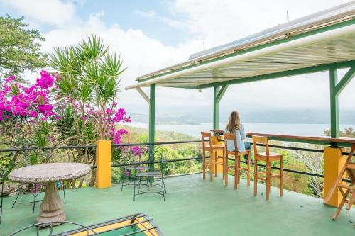 a woman sitting at a table on a balcony overlooking the ocean at Lake Arenal Hotel & Brewery in Tilarán