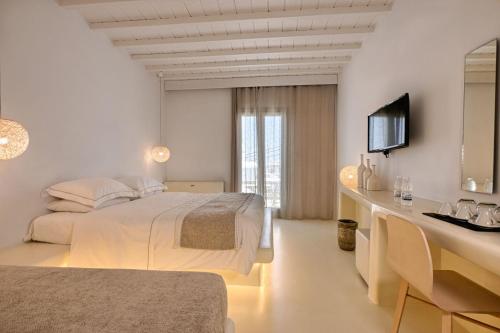 a white bedroom with a bed and a television at Nodo Boutique Hotel in Mýkonos City