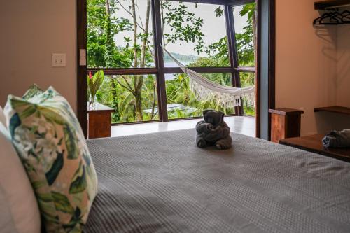 a stuffed elephant sitting on a bed with a window at Roam Yoga & Wellness Lodge in Bocas del Toro