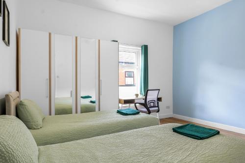 ein Schlafzimmer mit zwei Betten, einem Stuhl und einem Fenster in der Unterkunft Newly renovated 3 Ensuite bedroom house in bury, 5 people in Bury