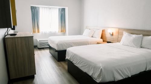 a hotel room with two beds and a window at Microtel Inn & Suites by Wyndham Gulf Shores in Gulf Shores