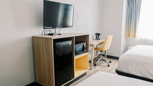 a room with a tv and a desk with a bed at Microtel Inn & Suites by Wyndham Gulf Shores in Gulf Shores