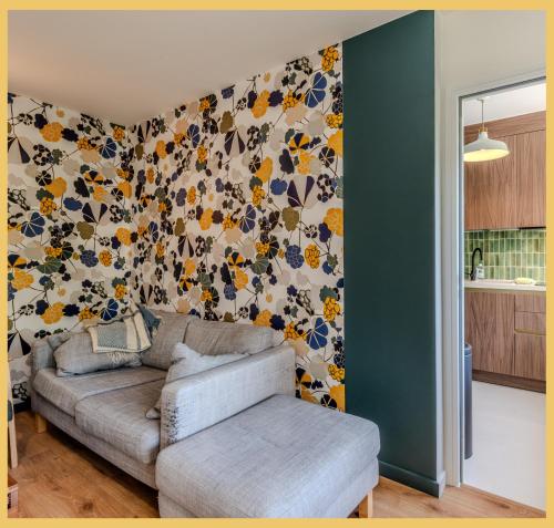 a living room with a couch and a floral wall at Chez Aiko I Appartement T3 I Ferney-Voltaire in Ferney-Voltaire