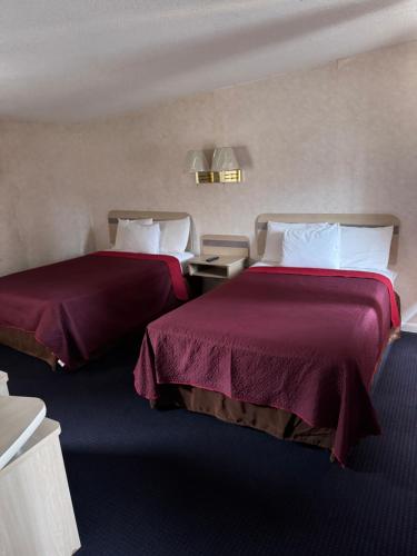 two beds in a hotel room with purple sheets at Sands Motel Niagara Falls in Niagara Falls