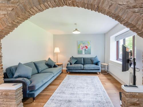Una sala de estar con dos sofás azules y un televisor. en The Farmhouse, en Hawes