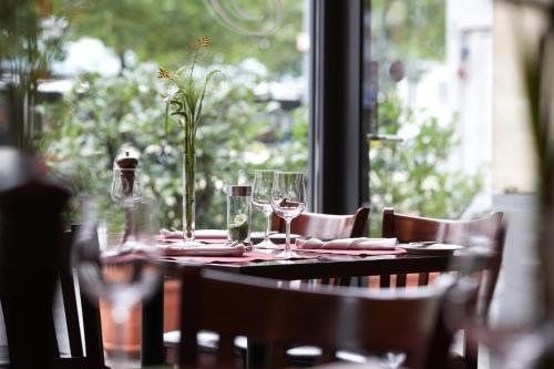 a table with glasses and a vase with flowers on it at IntercityHotel Bremen in Bremen
