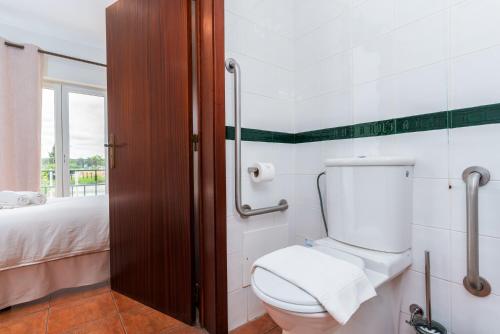 a bathroom with a toilet and a bed at Hotel Salatia in Alcácer do Sal
