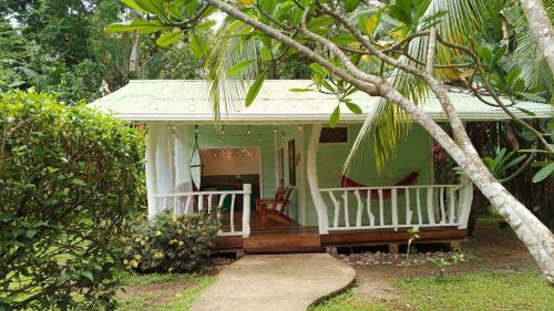 a small green house with a porch and a tree at La Rana De Cahuita in Cahuita
