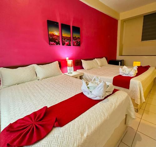 two beds in a room with a red wall at Hotel Barranquilla in Campeche