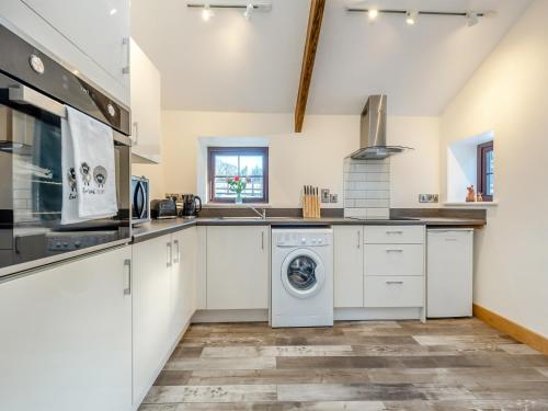 a kitchen with white cabinets and a washer and dryer at Ty Gwair - Uk41512 in Llanfair Clydogau