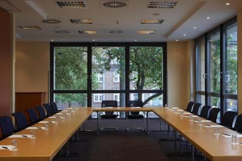 a large conference room with long tables and chairs at IntercityHotel Bremen in Bremen