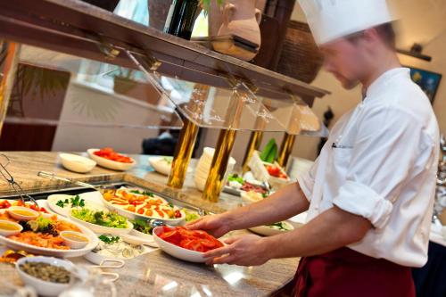 a chef preparing food in a restaurant kitchen at IntercityHotel Bremen in Bremen